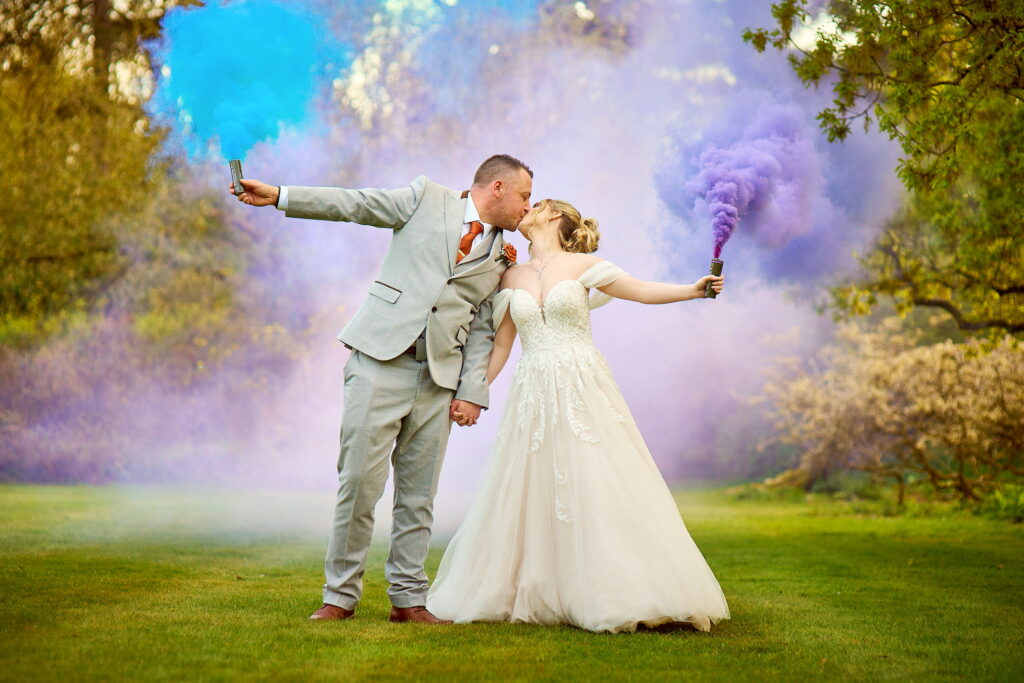 fantasy picture of the bride and groom holding coloured fireworks on wedding day